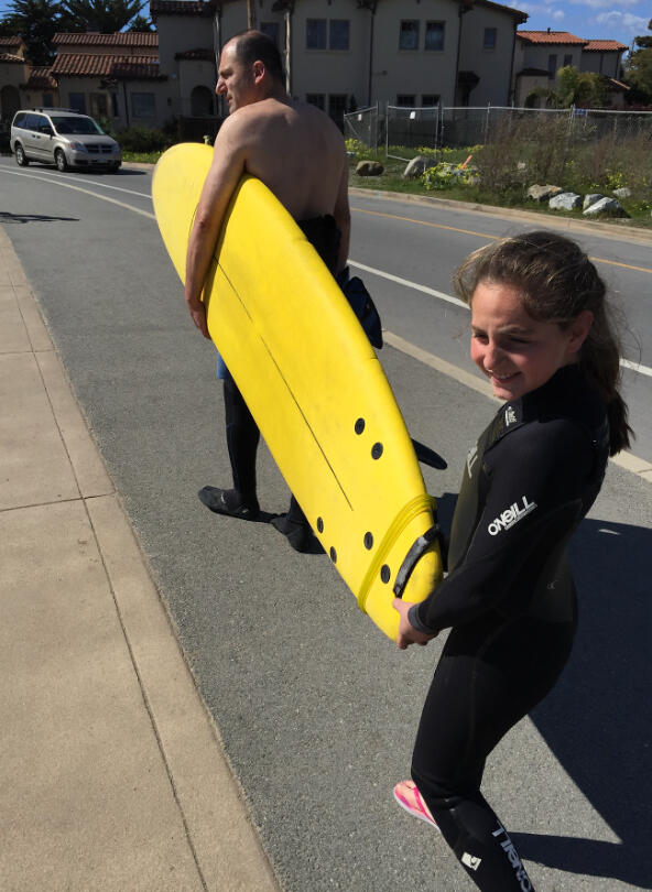 Emily Mitnick helping to carry a surf board on the way to the beach.