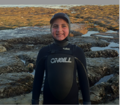 Emily Mitnick in a wetsuit with low tide pools behind her.