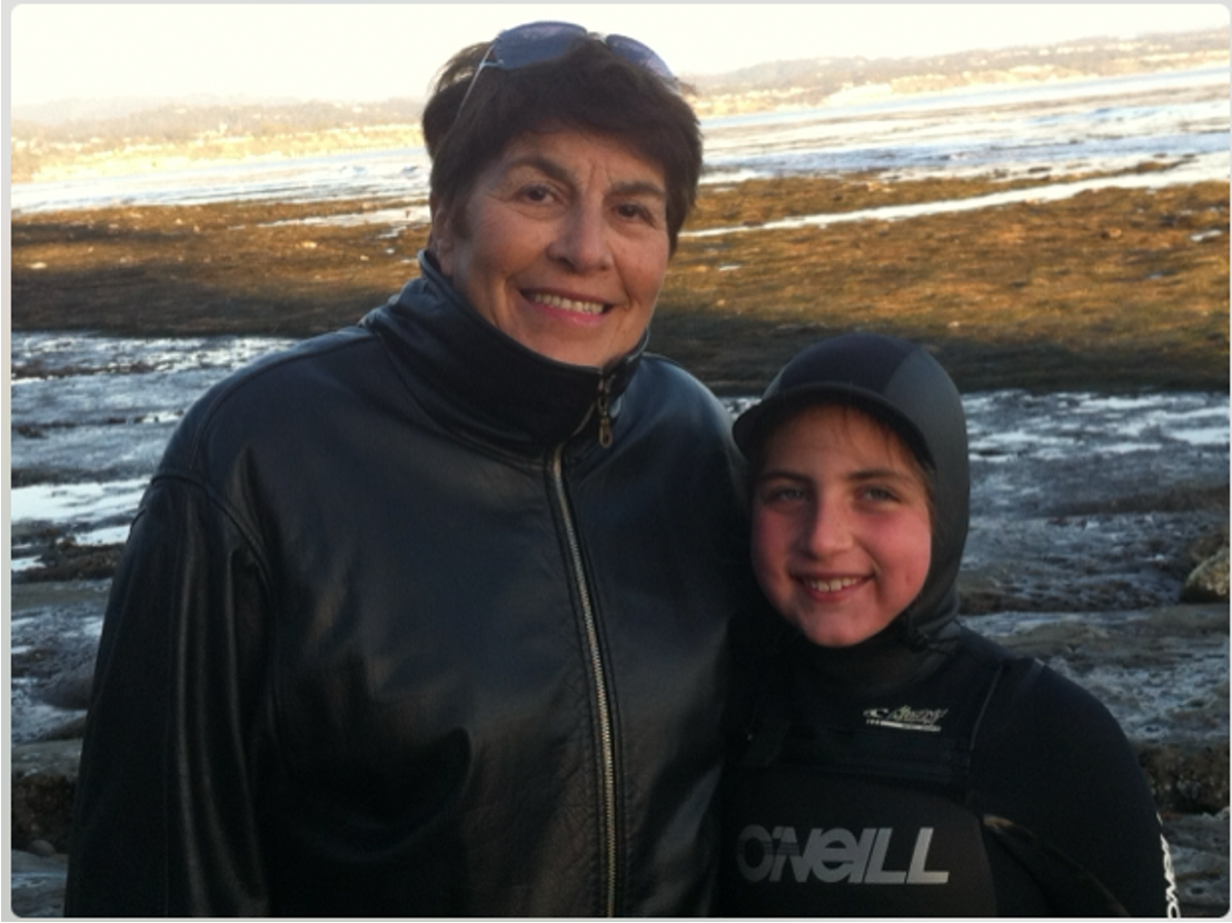 Emily Mitnick with her Grandma on the beac h with low tide pools on the background.